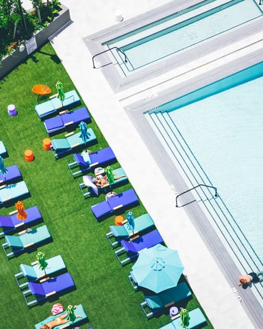 Resort-style swimming pool with spa, lounge chairs, and modern residential buildings surrounded by pine trees